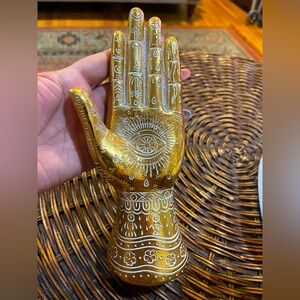 Gold henna hand statue with white 👁️🌖 motifs.